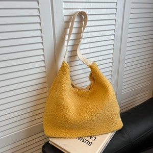 Yellow fuzzy teddy fabric tote bag with cream leather straps on a modern leather sofa