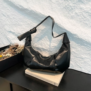Retro pleated black moon bag with bow shoulder strap shown in a modern lifestyle setting