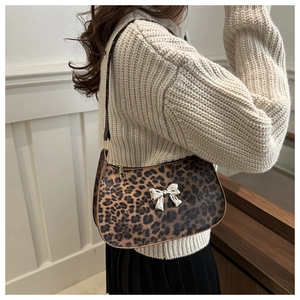 Detail of leopard print crossbody bag featuring a silver butterfly metallic ornament