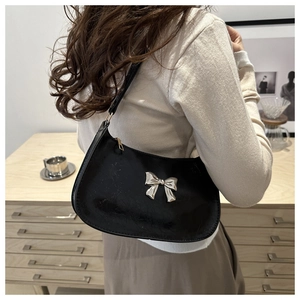Detail of black leather shoulder bag with silver bow accent and metallic zipper