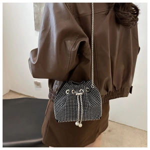 Detail of a black bucket bag with silver rhinestones, chain strap, and pearl charms