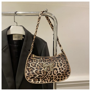 Detailed view of leopard print texture and golden butterfly charm on shoulder bag