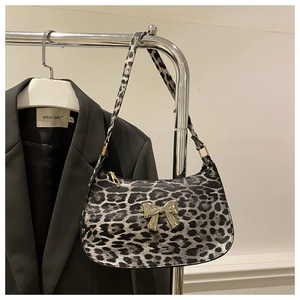 Macro detail of leopard print shoulder bag featuring a gold butterfly metal buckle