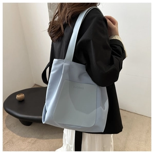 Close-up of light blue minimalist nylon tote bag with debossed lettering detail