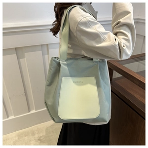 Detail of mint green tote bag featuring contrast front pocket and wide shoulder straps