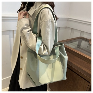 Detail of mint green nylon tote bag showing brand logo and shoulder strap texture