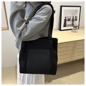 Close-up of black nylon tote bag with leather pocket and embossed BUDBAG logo detail