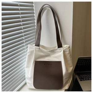Detail of white canvas tote bag with brown leather handles and front pocket