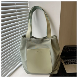 Close-up of light green tote bag featuring a leather front pocket and the BUDBAO logo detail