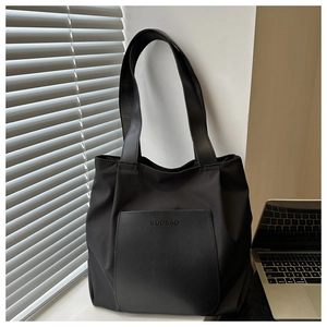 Close-up of a black large capacity nylon tote bag placed on a desk in an office setting