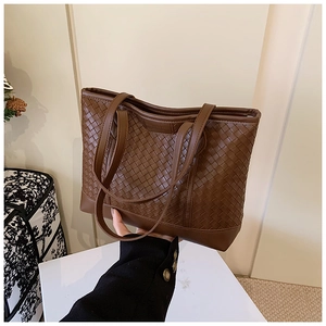 Detail of a brown woven tote bag featuring a high-quality checkered pattern and dual straps