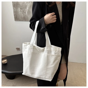 Minimalist white canvas tote bag with functional front pockets and sturdy handles