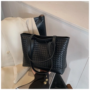 Close-up of black leather woven tote bag showing the large intrecciato weave detail
