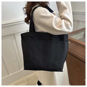 Detail view of black canvas tote bag showing multiple functional pockets and large capacity