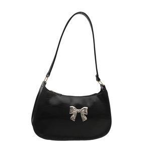 Glossy black leather baguette bag with a stylish silver metal bow and slim shoulder strap