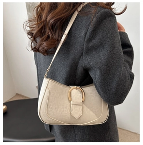 Beige Hobo-Tasche aus genarbtem Leder mit goldener Hufeisenschnalle an einem Model
