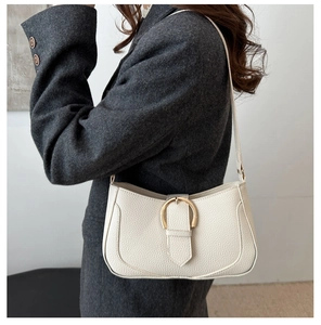 Detailansicht der cremefarbenen Halbmond-Tasche mit Lychee-Struktur und goldener Schnalle