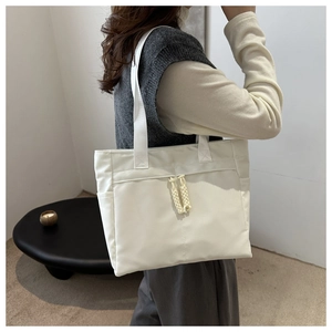 Detail of minimalist cream-white tote bag with woven zippers and wide shoulder straps