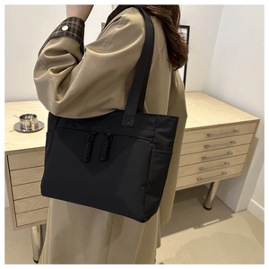 Détail du cabas noir en toile montrant les poches à double zip et compartiments