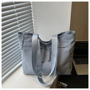 Close-up of fog blue tote bag with woven zippers and side pockets in office setting