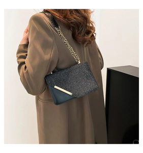 Detail of glitter shoulder bag with gold metal edge and fine chain strap on model