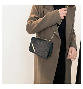 Close-up of black sequined crossbody bag with gold chain and metal diagonal accent