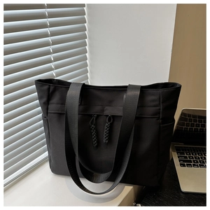 Detail of black canvas tote bag with side pockets on a professional office desk
