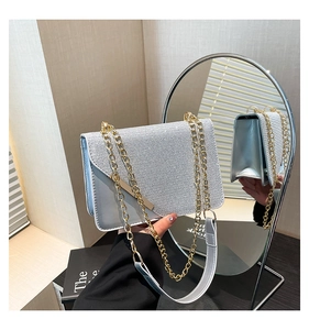 Side view of silver glitter crossbody bag showing depth and gold chain strap in mirror