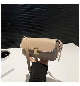 Close-up of beige leather crossbody bag with golden rectangular push-lock and shoulder strap