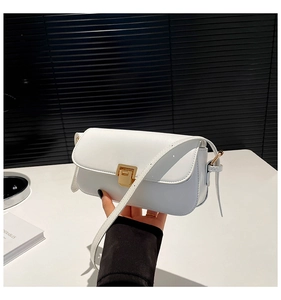 Detail of white faux leather crossbody bag with elegant gold metal buckle and hand-held strap
