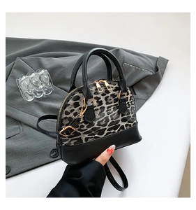 Detail of leopard print shell bag with golden hardware and black leather trim