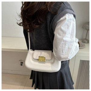 Close-up of a white leather crossbody bag featuring a unique gold chocolate bar lock
