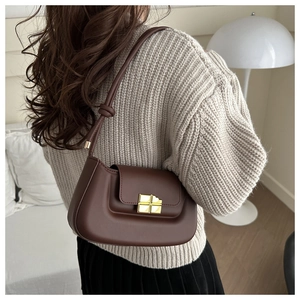 Detail of dark brown leather underarm bag with gold metal clasp and knotted strap accent