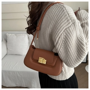 Detail of caramel leather underarm bag with unique chocolate-shaped gold buckle on model