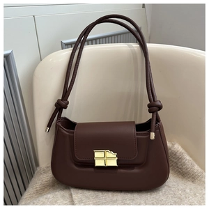 Detail of a chocolate-shaped gold lock on a premium brown leather crossbody bag
