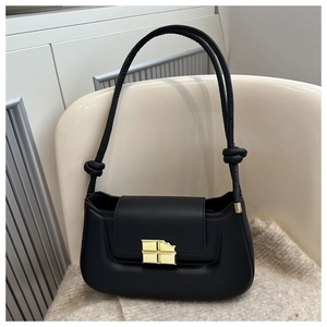 Close-up of elegant black matte PU leather bag with golden chocolate-shaped metal lock buckle