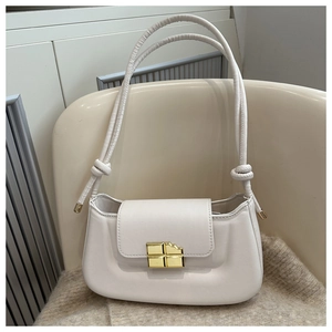 Close-up of a white shoulder bag featuring a unique golden chocolate-shaped metal clasp