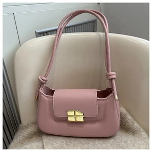 Detail of pink faux leather baguette bag featuring unique gold metal buckle on soft blanket