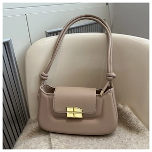 Detailed view of beige saddle bag featuring a creative bite-mark gold metal lock buckle