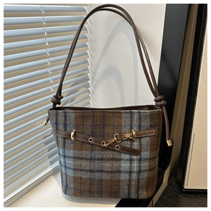 Close-up of textured plaid fabric and brown leather strap detail on women bucket bag