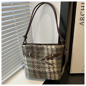 Close-up of winter vintage plaid tweed tote bag with leather strap and metal buckle detail