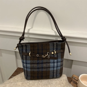 Detail of checkered wool tote with brown leather strap and metal ring hardware accents