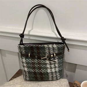 Detail of tweed bucket bag with green plaid pattern, leather drawstring and gold hardware