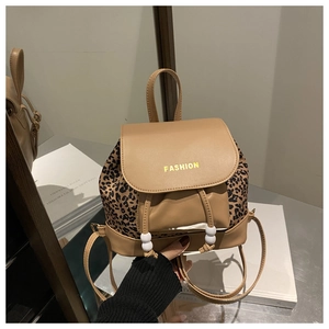 Detail view of small brown backpack featuring leopard print flap and FASHION lettering