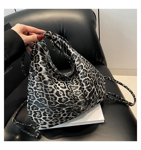 Gros plan du sac à bandoulière léopard avec détails dorés sur un canapé en cuir
