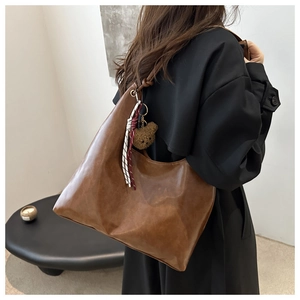Vue détaillée du sac hobo en cuir PU marron vintage avec breloque ours sur manteau noir