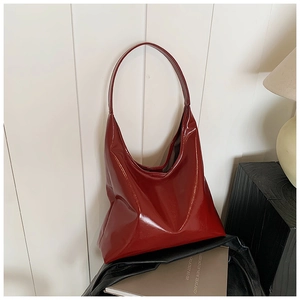 Detail of red patent leather hobo bag with glossy finish and wide shoulder strap