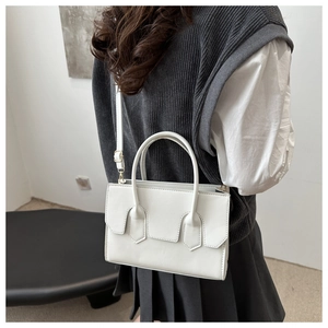 White faux leather crossbody bag with golden hardware and adjustable strap on a model