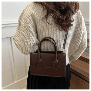 Side view of a brown vintage leather handbag with adjustable strap on a model shoulder