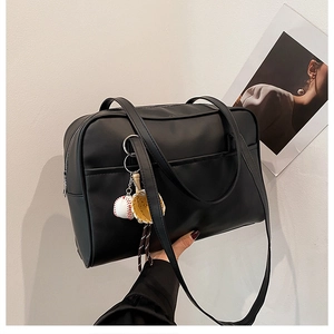 Close-up of black PU leather tote bag with baseball keychain accessory and smooth texture